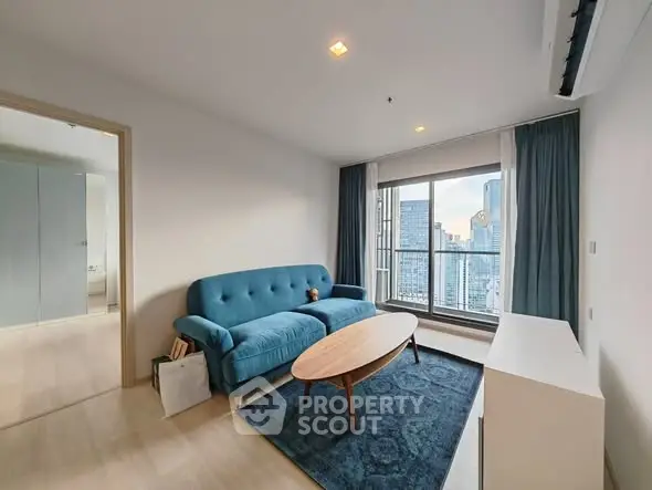 Modern living room with city view, blue sofa, and wooden coffee table.