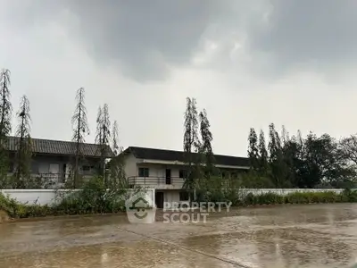 Spacious industrial property with large paved area and lush greenery, ideal for commercial use.