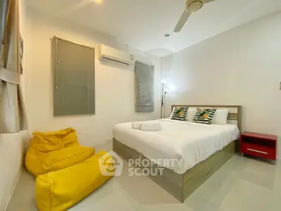 Cozy bedroom with modern decor, featuring a comfortable bed, air conditioning, and stylish yellow bean bag chairs.