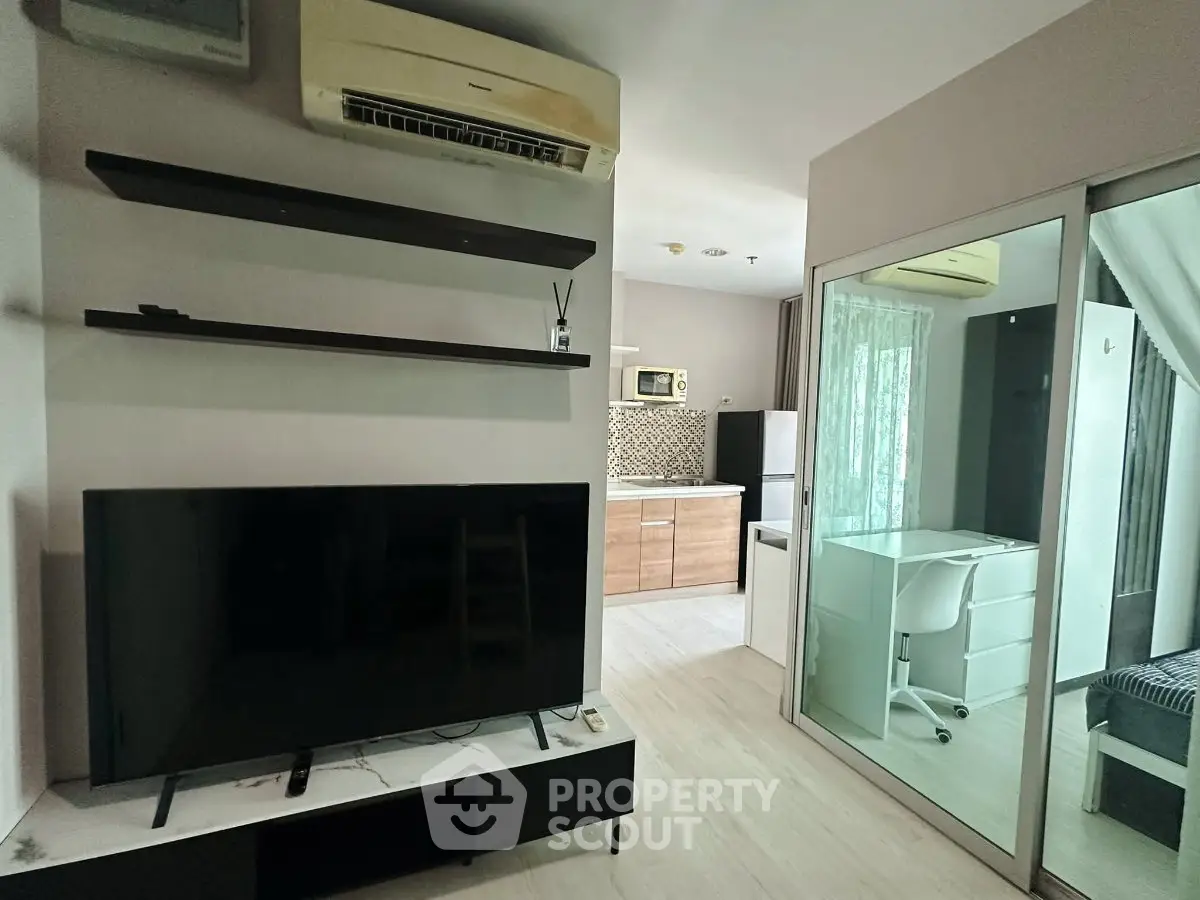 Modern apartment interior with TV, air conditioning, and compact kitchen area.