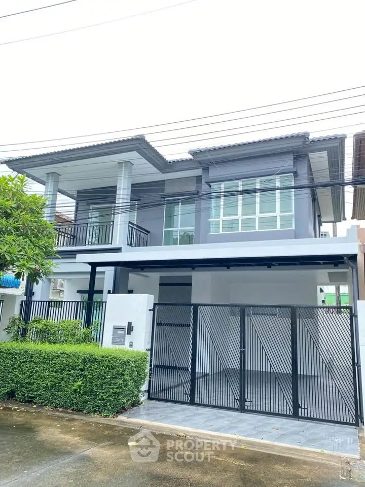 Modern two-story house with sleek design and gated entrance in a suburban neighborhood.