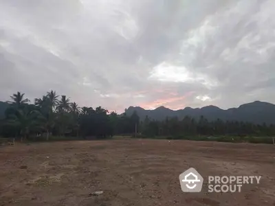 Scenic land plot with mountain backdrop and lush greenery, ideal for development or investment.