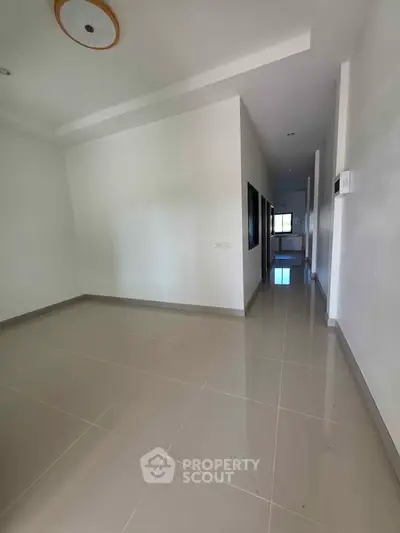 Spacious empty room with glossy tiled floor and modern ceiling light, perfect for customization.