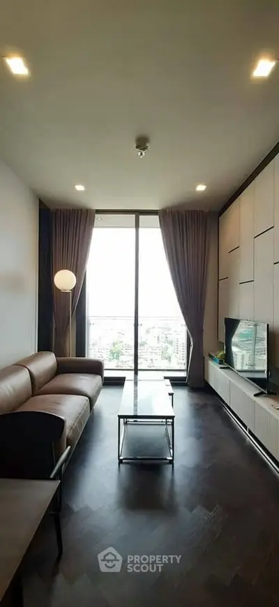 Modern living room with large window and stylish furniture in high-rise apartment.