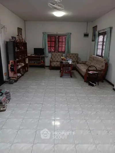 Spacious living room with tiled floor and cozy furniture, perfect for family gatherings.