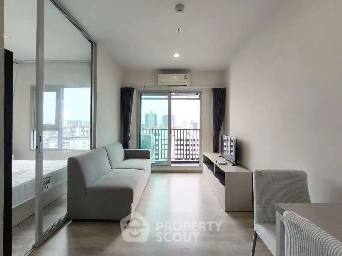 Modern living room with city view, sleek furniture, and natural light in a high-rise apartment.