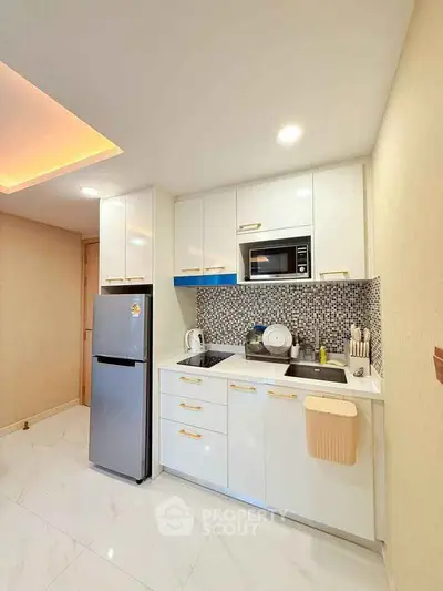 Modern kitchen with sleek cabinetry, stainless steel fridge, and stylish backsplash in a cozy apartment.
