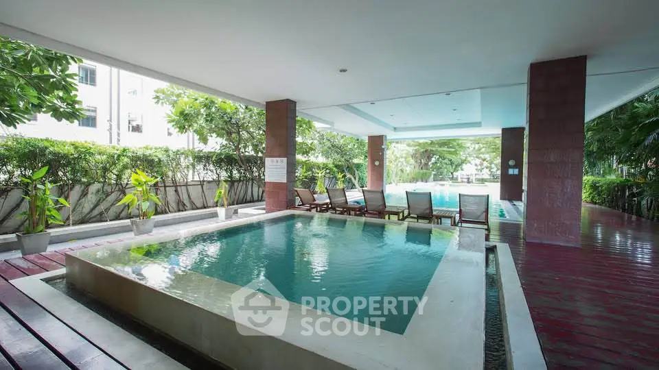 Luxurious condominium pool area with lush greenery and modern design.