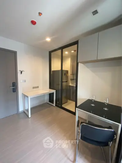 Modern apartment interior with compact kitchen and dining area, featuring sleek design and efficient use of space.