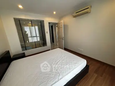 Modern bedroom with wooden flooring and air conditioning unit