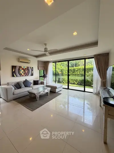 Spacious living room with large windows and garden view, featuring elegant furniture and modern decor.