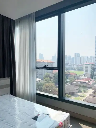 Spacious bedroom with large windows offering stunning city views in a modern high-rise apartment.
