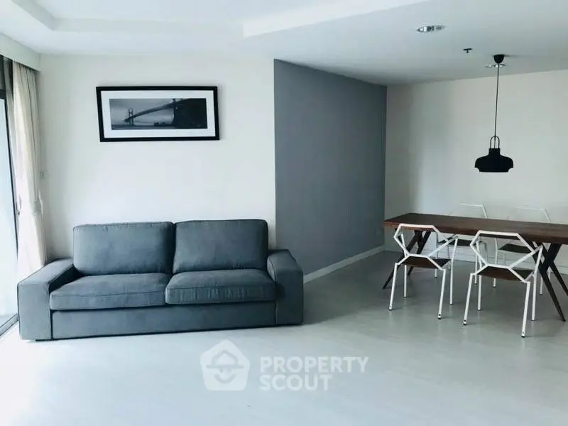 Modern living room with gray sofa and stylish dining area