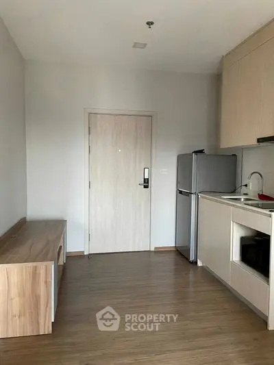 Modern kitchen with sleek cabinetry and compact fridge in a cozy apartment.