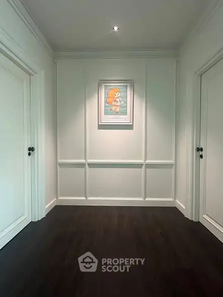 Elegant hallway with dark wood flooring and framed artwork, showcasing modern interior design.
