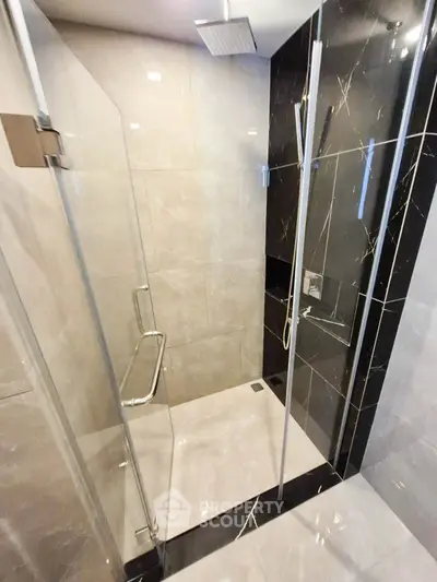 Modern bathroom with sleek glass shower and elegant black marble accents.