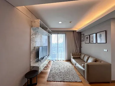 Modern living room with sleek marble TV wall and cozy sofa, featuring elegant decor and natural light.