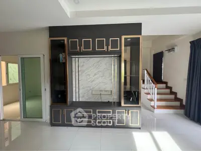 Spacious modern living room with elegant built-in shelving and staircase, perfect for stylish living.