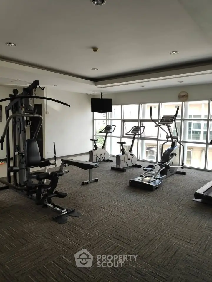 Modern gym with exercise equipment and large windows in a residential building.