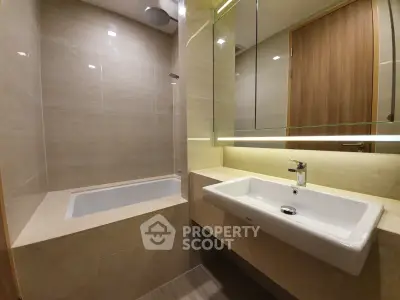 Modern bathroom with sleek design featuring a bathtub and elegant sink.