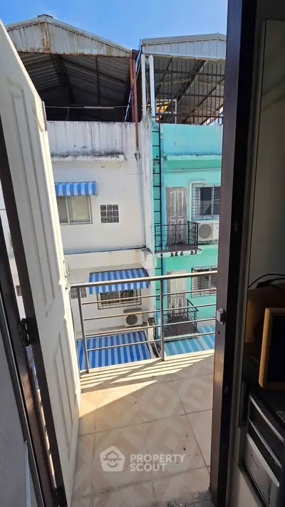 Charming balcony view with vibrant building exteriors and blue awnings, perfect for urban living enthusiasts.