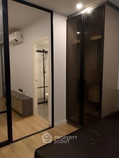Modern bedroom with glass wardrobe and view into sleek bathroom