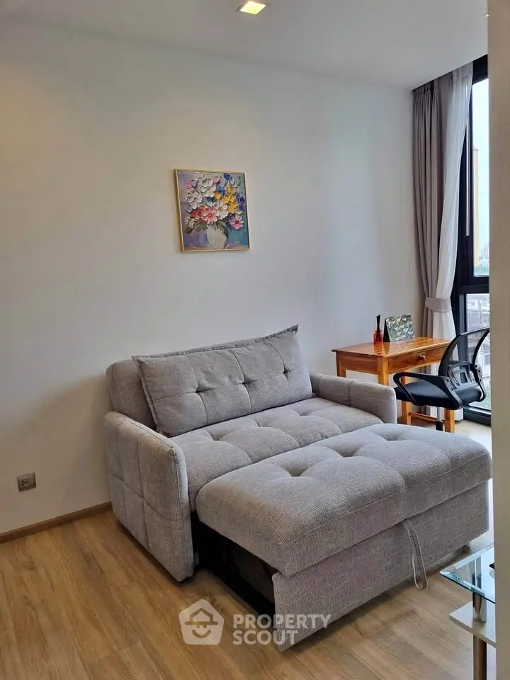 Modern living room with stylish sofa bed and work desk, featuring elegant decor and natural light.