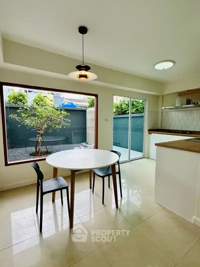 Modern kitchen with open layout and garden view, featuring sleek dining area and natural light.