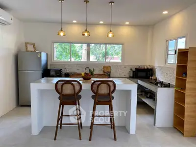 Modern kitchen with open layout, featuring a sleek island, stylish bar stools, and contemporary lighting.