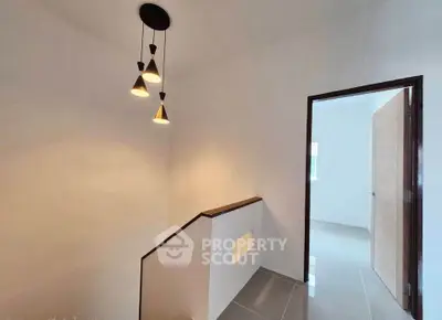Modern interior hallway with stylish pendant lighting and sleek tile flooring.