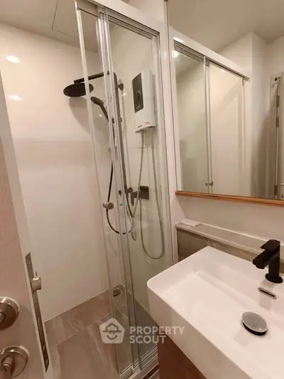 Modern bathroom with sleek shower and stylish sink in contemporary apartment.