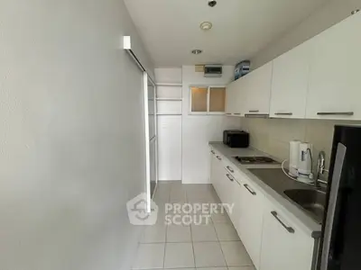 Modern kitchen with sleek white cabinets and stainless steel appliances in a compact layout.