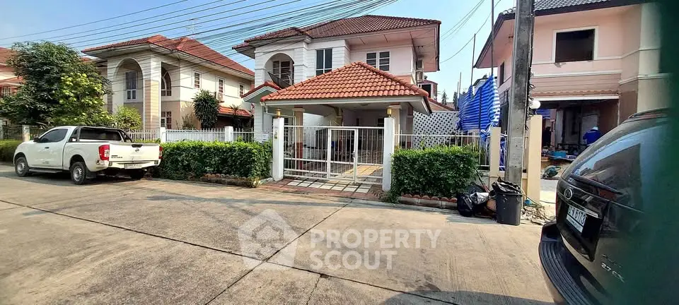 Charming suburban house with red-tiled roof and gated entrance in a quiet neighborhood.