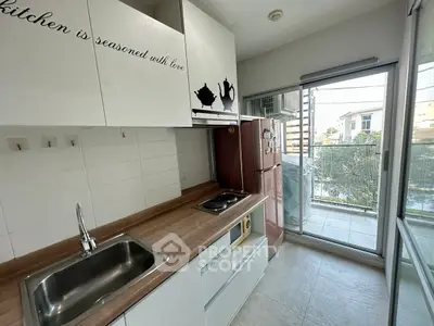 Modern kitchen with balcony access, featuring sleek cabinetry and stainless steel sink.
