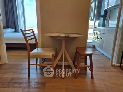 Cozy apartment interior with wooden flooring, small dining table, and modern kitchen view.