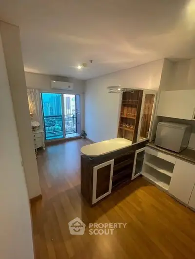 Modern apartment interior with open kitchen and balcony view in urban setting.