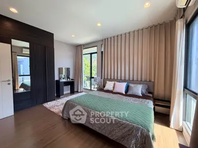 Spacious bedroom with modern decor and large windows offering natural light.
