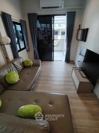 Modern living room with stylish decor and balcony access, featuring sleek furniture and natural light.