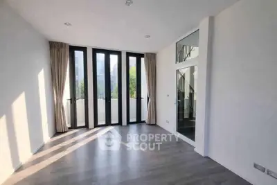 Spacious modern living room with floor-to-ceiling windows and elegant curtains, offering abundant natural light.