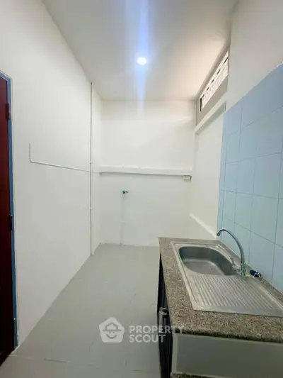 Compact kitchen with granite countertop and stainless steel sink in a minimalist design.