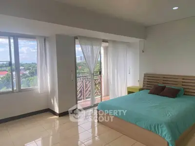 Spacious bedroom with large windows and balcony access, offering a serene view.