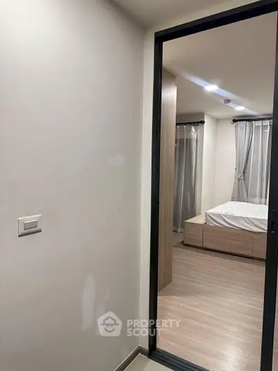 Modern bedroom with wooden flooring and sliding door, featuring a cozy bed and elegant curtains.