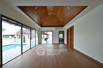 Spacious modern living room with wooden ceiling and pool view