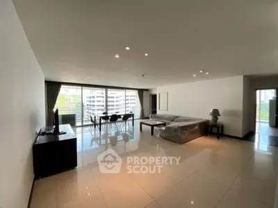 Spacious modern living room with large windows and balcony view in urban apartment.