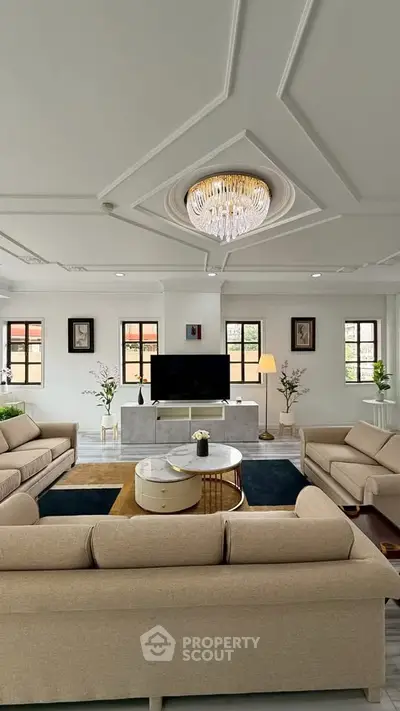 Luxurious living room with elegant chandelier and modern furniture, perfect for stylish entertaining.