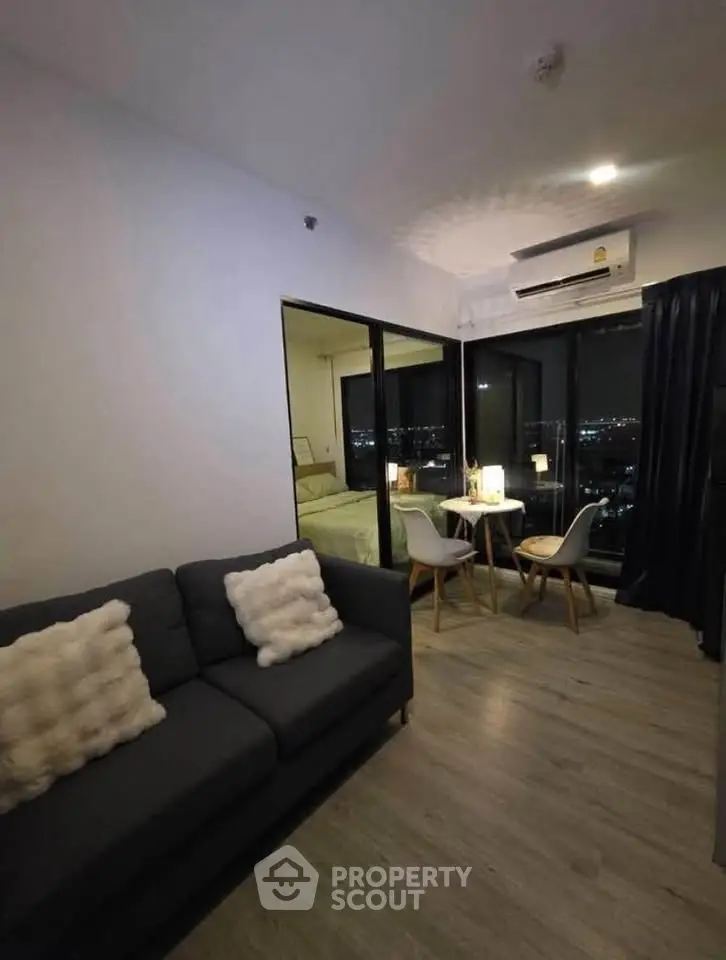 Modern living room with city view, cozy seating, and dining area in a stylish apartment.