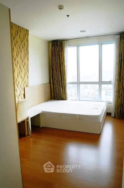 Bright bedroom with large window and wooden flooring, featuring modern decor and ample natural light.