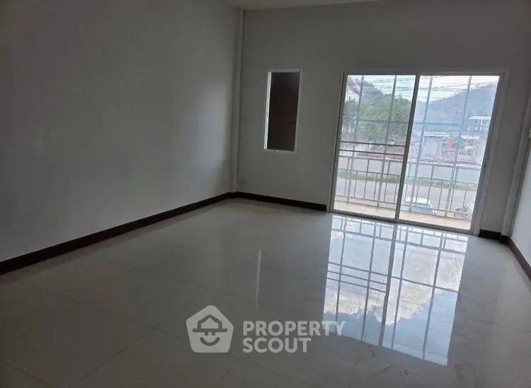 Spacious empty room with large windows and balcony access, offering natural light and scenic views.