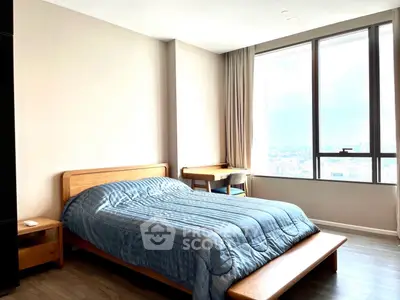 Spacious bedroom with large windows offering stunning city views and modern furnishings.