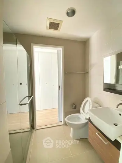 Modern bathroom with sleek fixtures and large mirror in a contemporary apartment.